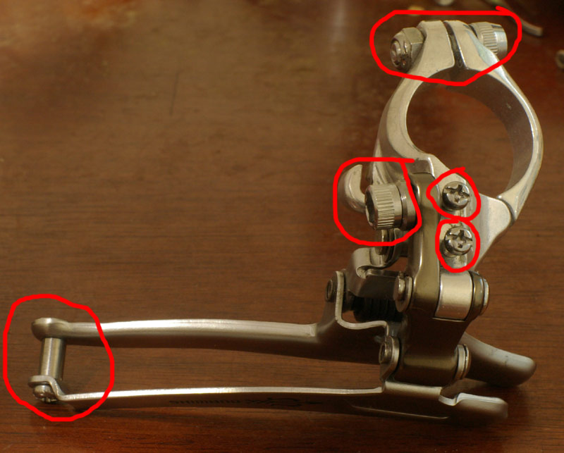 These are the parts a front derailer has that can be lost. On the left is the screw that holds the cage together. The two similar screws limit the derailer's travel, and the one next to them holds the cable. The screw at the top holds the derailer to the frame.